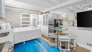 A modern kitchen with white cabinetry, a built-in refrigerator, and a dining area with a round table and bar stools. - Beachfront Studio w/ Pool, Steps to Sand, Sleeps 3 (Panama City Beach)