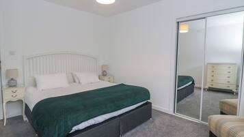 A bedroom with a bed, a nightstand, a dresser, and a sliding door closet.