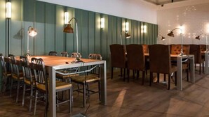 Een vergaderruimte met een lange tafel, meerdere stoelen en hanglampen.
