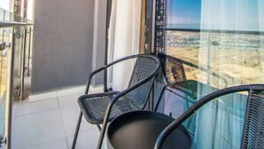 Ein Balkon mit Stuhl, Glastür und Blick auf die Stadtlandschaft.
