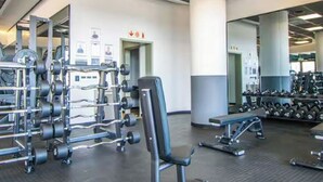 Ein Fitnessstudio mit Krafttrainingsgeräten, Bänken und einer Spiegelwand.