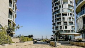 Ein modernes, mehrstöckiges Gebäude mit Balkonen, blauem Himmel und einem gepflasterten Gehweg.