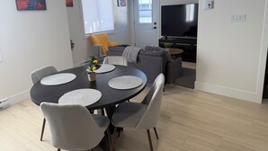 Uma sala de jantar com uma mesa redonda, cadeiras cinzentas e um vaso de planta.