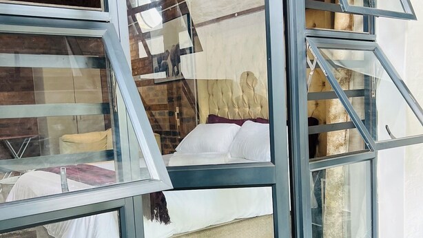 Een slaapkamer met een bed, een raam en een trap.