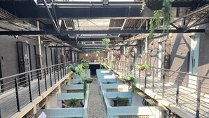 Een binnencorridor met een centrale doorgang, metalen leuningen en hangende planten.