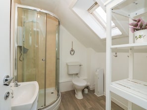 A bathroom with a glass-enclosed shower, a white sink, a toilet, and a shelf with decorative items. - Hawthorn (Inveraray)