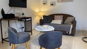 Ein modernes Wohnzimmer mit Flachbildfernseher, einer Couch, zwei Sesseln, einem Couchtisch und einer Weltkarte an der Wand.