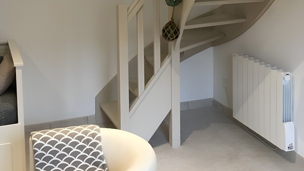 Eine Treppe mit Holzbalken, einer weißen Wand und einem Heizkörper.