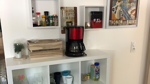Eine Küchenzeile mit einer Kaffeemaschine, Regalen mit Geschirr und einem dekorativen Poster an der Wand.