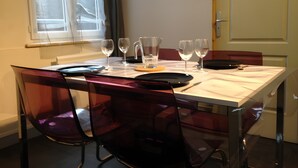 Uma mesa de jantar com cadeiras, jarra, copos e pratos para quatro pessoas.