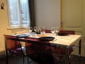 A dining table with chairs, a pitcher, glasses, and a plate set for four. - L'orchidée: Your Apartment in the Heart of Honfleur (Honfleur)