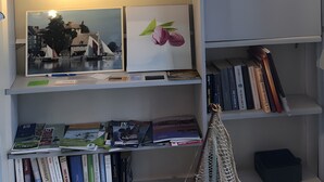 Uma estante com diversos objetos, incluindo livros, revistas e fotografias emolduradas.