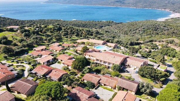 Un quartier résidentiel situé sur la côte, avec des maisons, une piscine et une vue sur la mer.