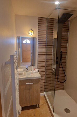 A bathroom with a shower, a sink with a mirror, and a towel rack.