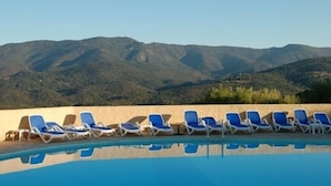 Ein Pool mit blauen Liegestühlen und Blick auf die Berge.