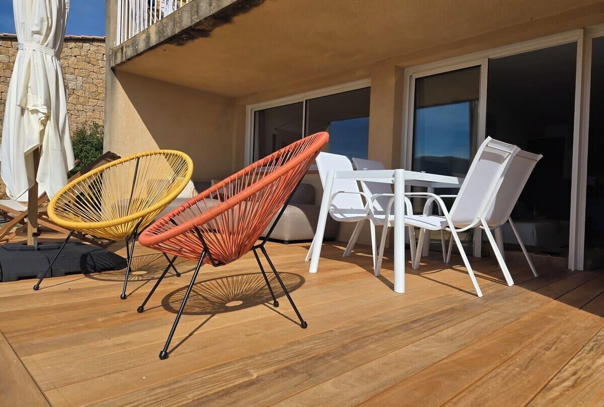 An outdoor patio with wicker chairs, a white table, and a stone wall.