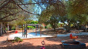 Ein Spielplatz mit Klettergerüst, Schaukeln und Sandkasten.