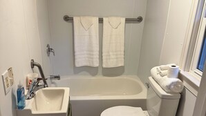 Un baño pequeño con bañera, inodoro y lavabo.