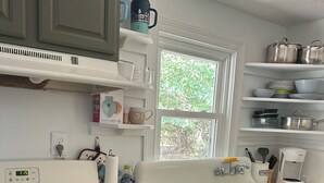 Una cocina con estufa, lavaplatos y diferentes utensilios de cocina en estanterías.
