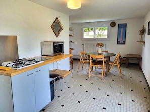 Une cuisine équipée d’une cuisinière à gaz, d’un four à micro-ondes et d’un coin repas avec une table et des chaises.