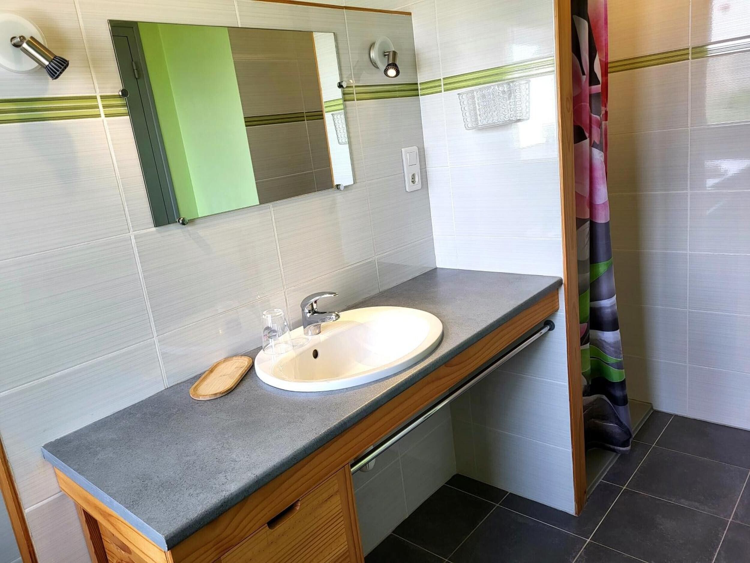 A bathroom with a sink, mirror, and shower curtain.