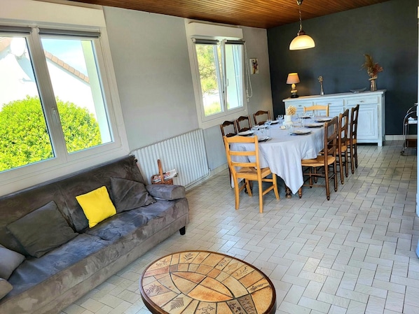 Un coin repas avec une table dressée pour quatre personnes, un canapé avec des coussins et un radiateur.