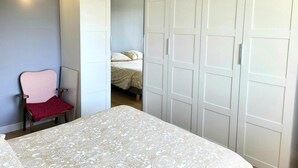 Ein Schlafzimmer mit Bett, Sessel und Kleiderschrank.