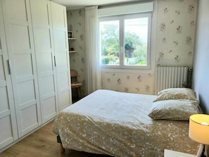 Une chambre à coucher avec un lit, une fenêtre, un radiateur et une armoire.