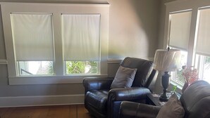 Uma sala de estar com um sofá de couro, uma luminária e uma janela com persianas.