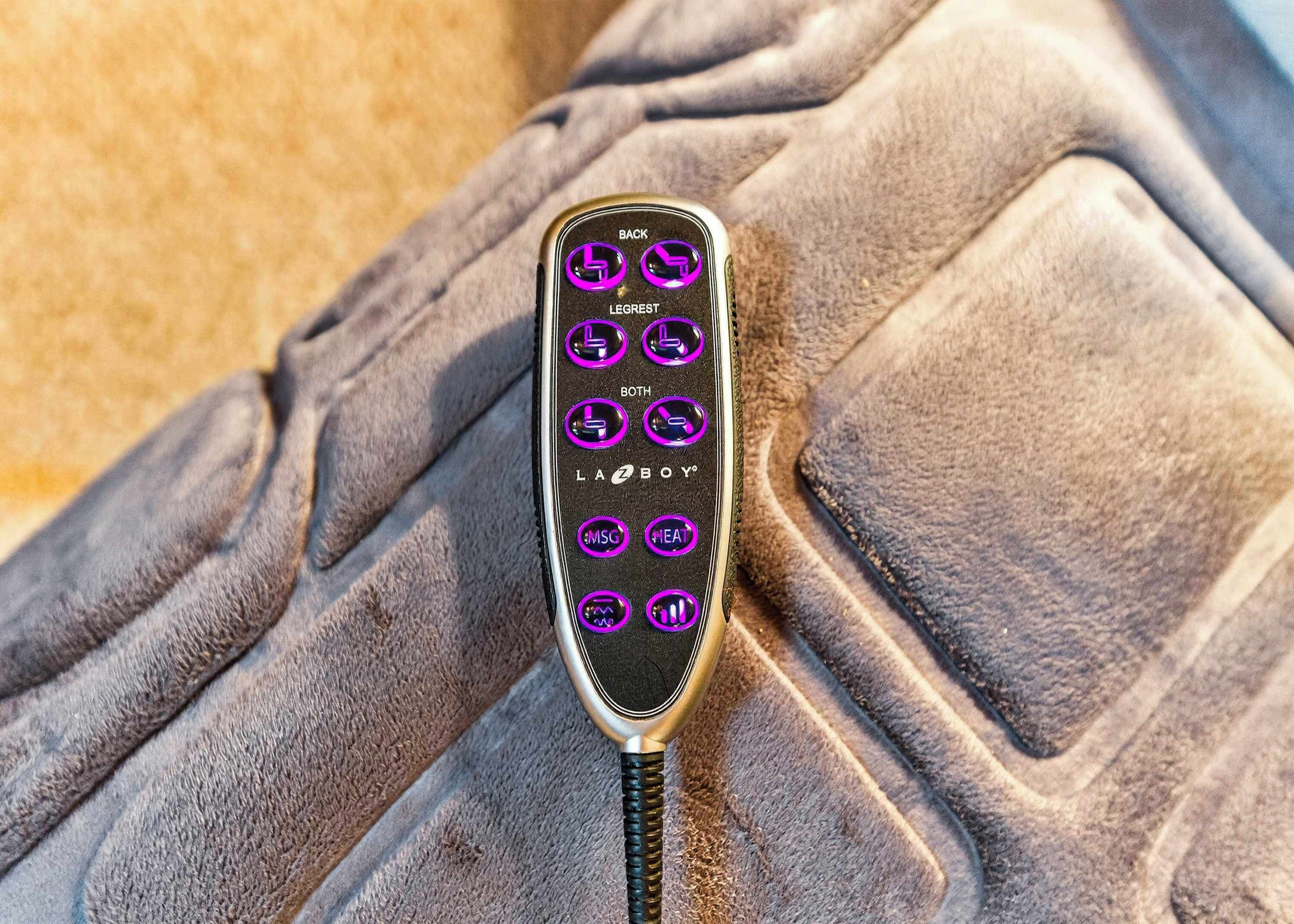 Une télécommande de voiture dotée de plusieurs boutons, notamment « RETOUR », « REPOSE-PIEDS », « TOUS », « LAZEBOY », « MASSAGE » et « CHALEUR ».