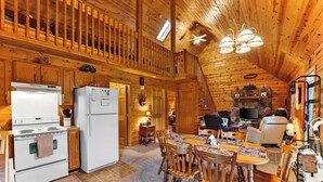 Interior d'una cabana de fusta amb cuina, zona de menjador i sala d'estar.