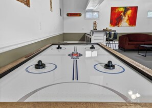 Una habitación con una mesa de juego de discos, un sofá rojo y un cuadro en la pared.
