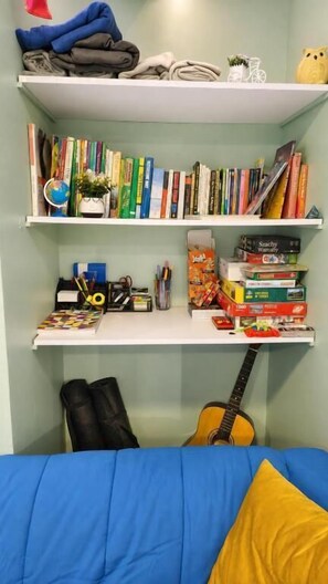Ein Zimmer mit einem Bett, einem Bücherregal und einer Gitarre.