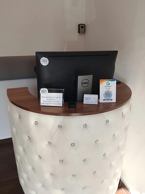 A reception desk with a Dell computer, a Google QR code, and a sign instructing to press a button to call the receptionist. - Dzien Dobry Hostel (Gdańsk)