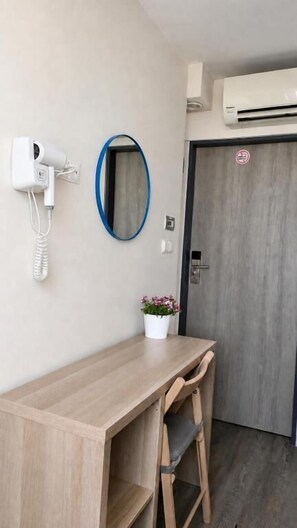 A room with a wooden desk, a chair, a wall-mounted hairdryer, a mirror, and a door with a padlock. - Dzien Dobry Hostel (Gdańsk)