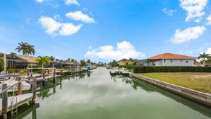 Un canal con barcos amarrados a ambos lados, flanqueado por edificios residenciales y palmeras.