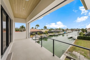 A balcony with a view of a marina, a clear sky, and a distant landscape with palm trees. - Ostentatious Home Short Walk to Beach, Food and fun (Marco Island)