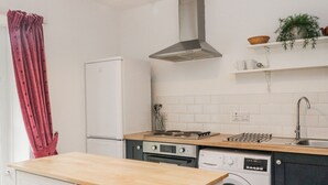 Een keuken met een fornuis, oven, vaatwasser en een wasmachine.