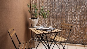 Een klein buiten zitgedeelte met een tafel, stoelen, een bloempot en een decoratieve muur.