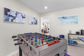 A room with a foosball table, abstract wall art, and a ping pong table. - 737 Nautilus Court (Marco Island)