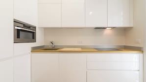 Une cuisine moderne avec des meubles blancs, un four en acier inoxydable, un évier et un plan de travail en bois.