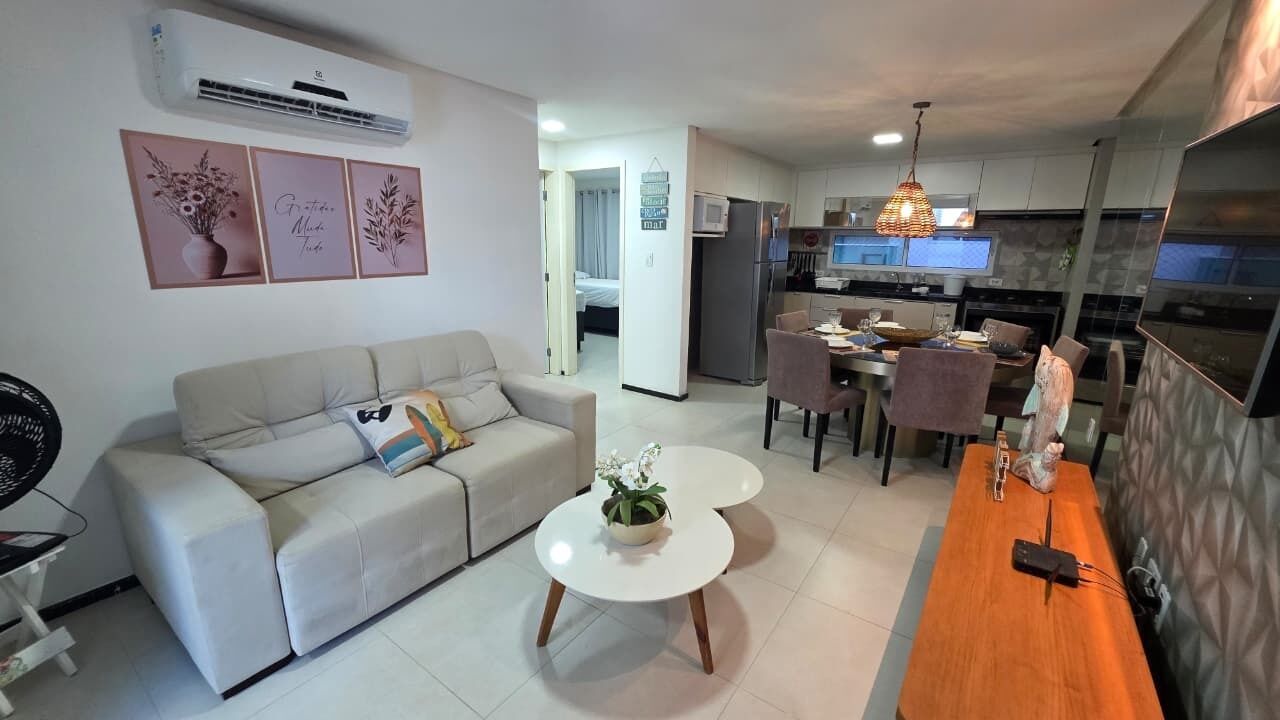 A modern living room with a sofa, a coffee table, and a dining area with chairs.