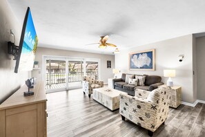 A living room with a ceiling fan, a television, a sofa, a coffee table, and a patterned armchair. - 1672 Barbarosa Court (Marco Island)