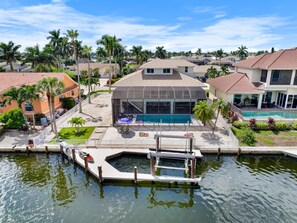 A residential property with a swimming pool, dock, and surrounding greenery. - 1672 Barbarosa Court (Marco Island)