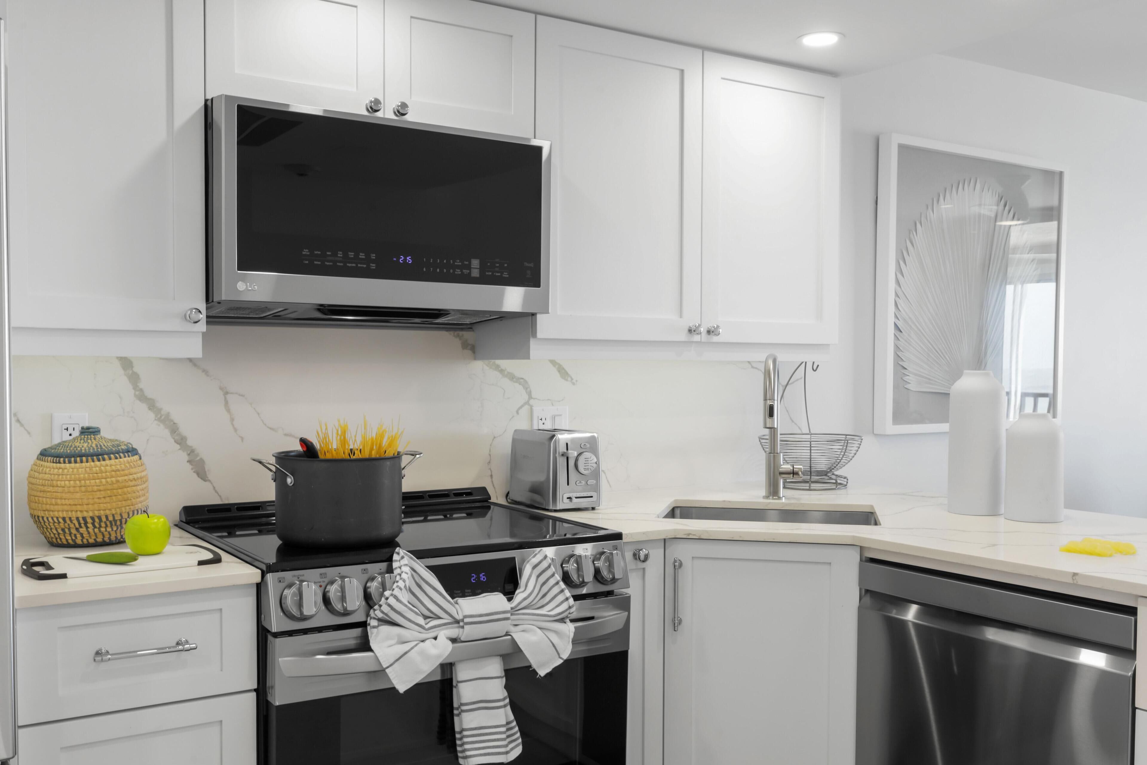 A modern kitchen with white cabinets, a stainless steel stove, a microwave, and a toaster.