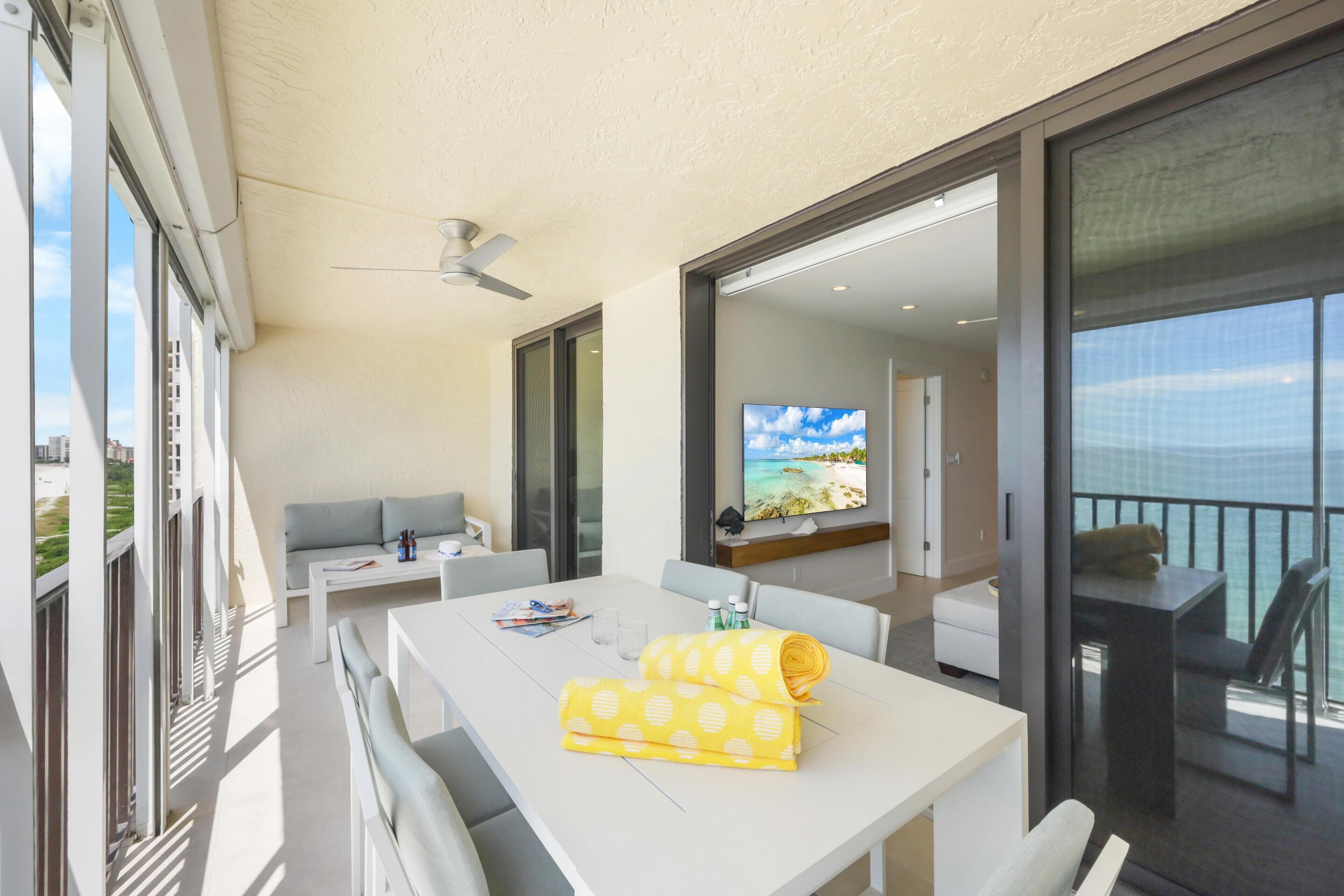 A balcony with a dining table, a sofa, and a TV.