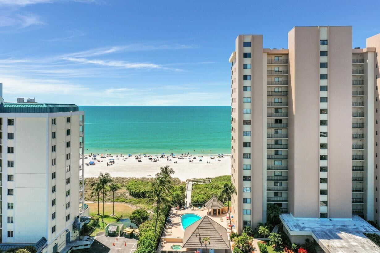 A high-rise hotel with a view of the beach and a pool area.