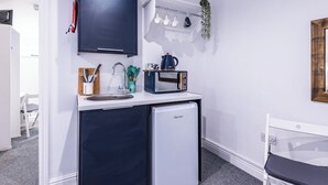 Une cuisine compacte équipée d’un réfrigérateur, d’un four à micro-ondes, d’un évier et d’un téléviseur à écran plat.