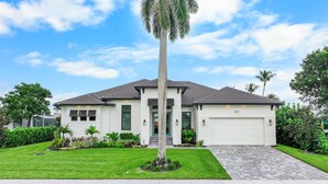 A single-story house with a garage, a well-maintained lawn, and a palm tree. - 811 Apple Court (Marco Island)