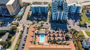 Ein Hotelkomplex am Meer mit mehreren Hochhäusern, einem zentralen Poolbereich und Blick auf den Strand.